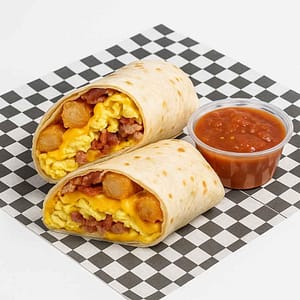 A hyper-realistic image of a Classic Breakfast Burrito cut in half, filled with scrambled eggs, crispy tater tots, melted cheese, and bacon, served with a side of salsa on black-and-white checkered deli paper. Perfect for anyone searching for a Burrito near me in Newport News