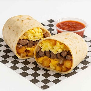 A hyper-realistic image of a Steak & Egg Breakfast Burrito cut in half, filled with grilled steak, scrambled eggs, crispy tater tots, caramelized onions, and melted cheese, served with a side of salsa on black-and-white checkered deli paper. Perfect for anyone searching for a Burrito near me in Newport News.