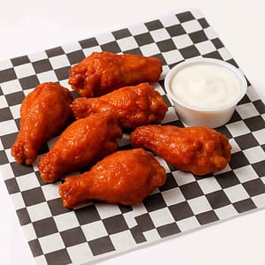 Hyper-realistic Buffalo Wings on check deli paper, six crispy wings coated in tangy buffalo sauce, served with a side of creamy dipping sauce. Perfect spicy wings or lunch near me in Newport News.