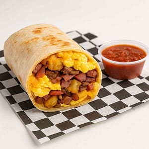 A hyper-realistic image of a Meat Eater Breakfast Burrito cut open to show scrambled eggs, crispy tater tots, melted cheese, bacon, ham, and sausage, wrapped in a golden tortilla and served with a side of salsa on black-and-white checkered deli paper. Perfect for anyone searching for a Breakfast Burrito near me or Meat Lover’s Burrito in Newport News.